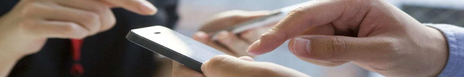 Close de duas mãos segurando um smartphone e uma caneta, com foco na interação com o dispositivo.
