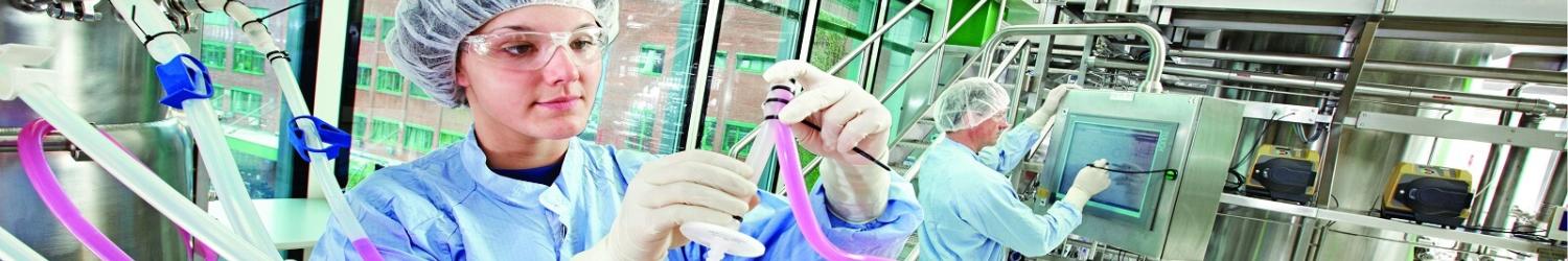 Um técnico com equipamento de proteção manuseia equipamentos e tubos de laboratório em um laboratório industrial.
