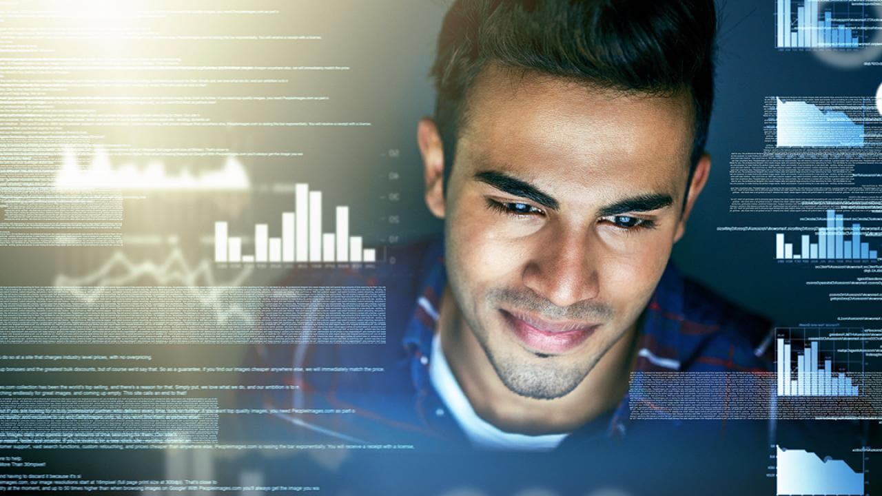 Um homem olha para vários gráficos digitais e exibições de dados em uma tela.