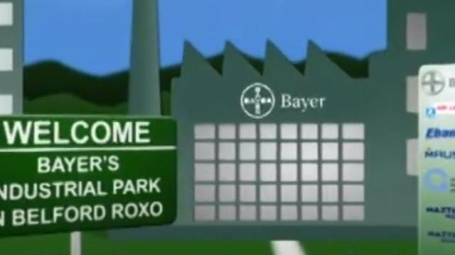 Placa no parque industrial da Bayer em Belford Roxo com logotipos da empresa ao fundo.