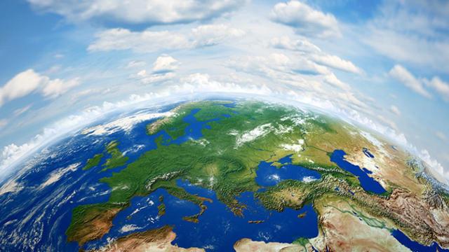 Vista aérea da Terra mostrando a Europa, partes da Ásia e África, com nuvens dispersas em um céu azul brilhante.